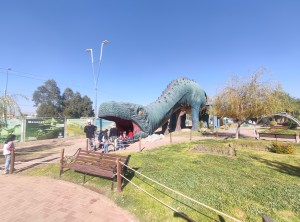Visita al parque, se ve un gran dinosaurio y a los niños jugando